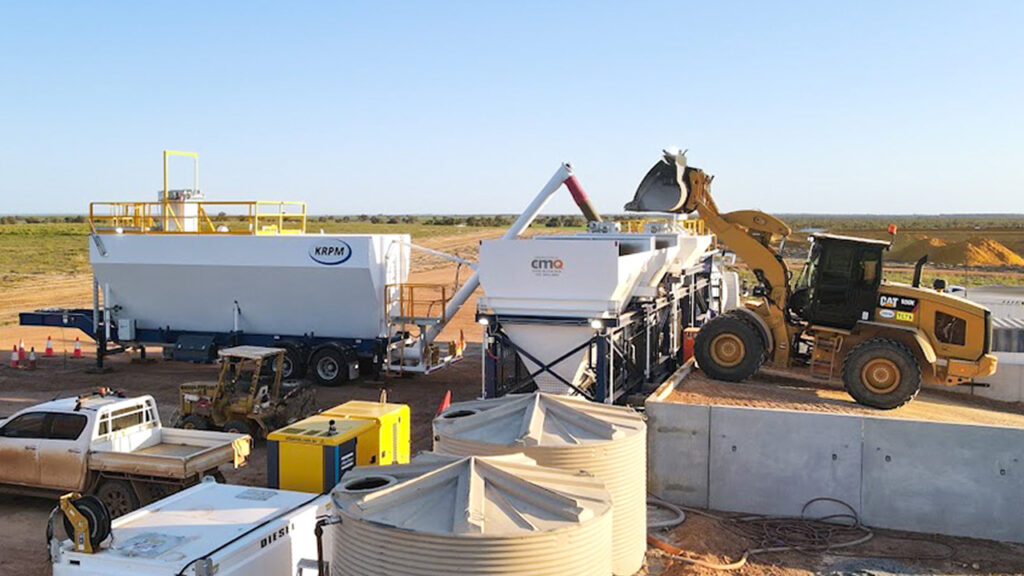 View of DualBatch portable concrete plant shows aggregate weigh hoppers being loaded with a front-end loader. This view also shows the portable cement silo.