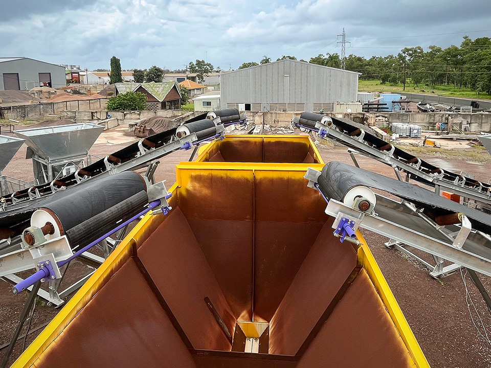 View showing the aggregate weigh hoppers of the DualBatch™ portable concrete plant being loaded with five optional aggregate boot bins & conveyors.
